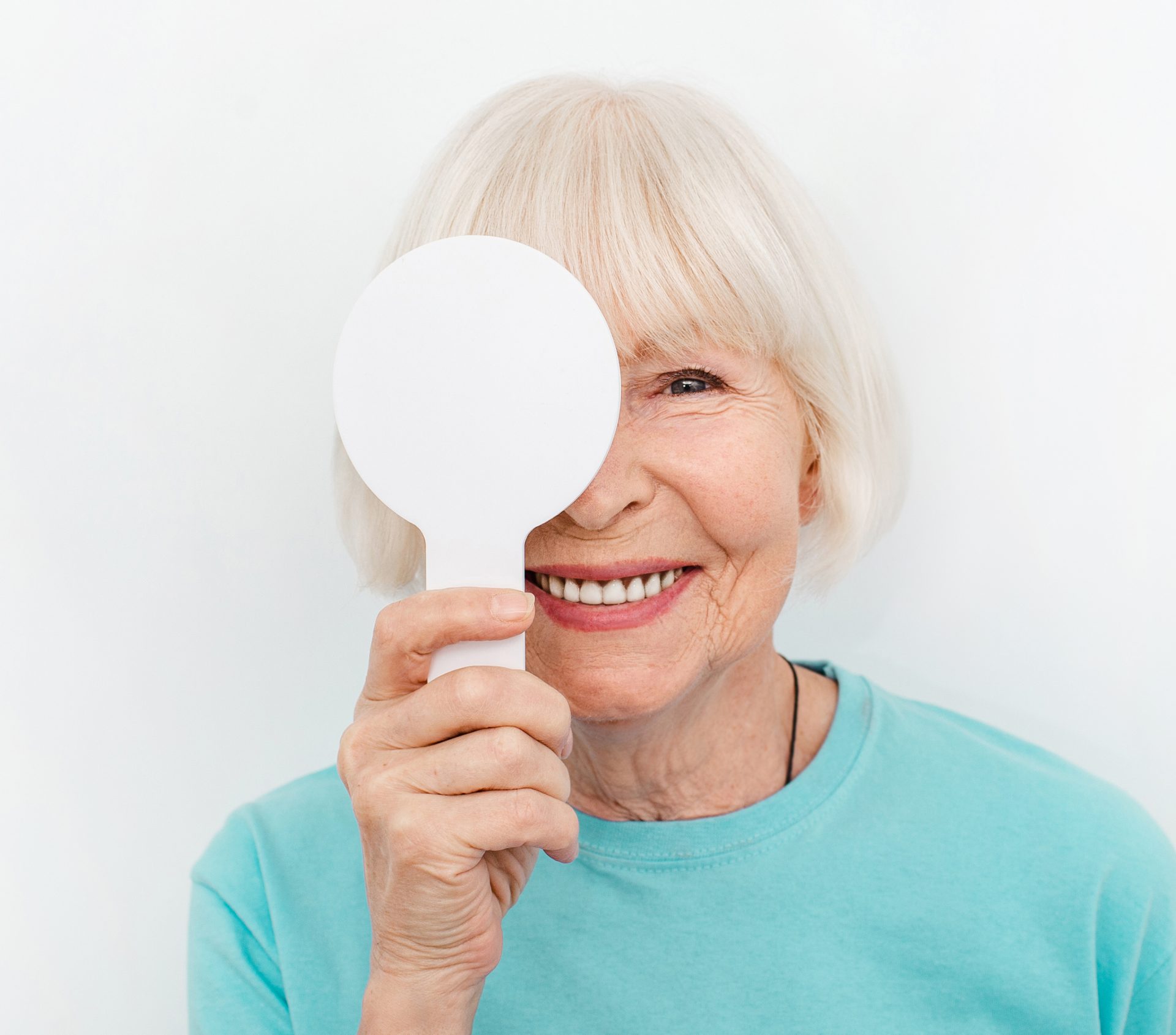 Senior woman having an eye exam with one eye covering using a special tool, on a white background. Eye test elderly patient. Vision test concept